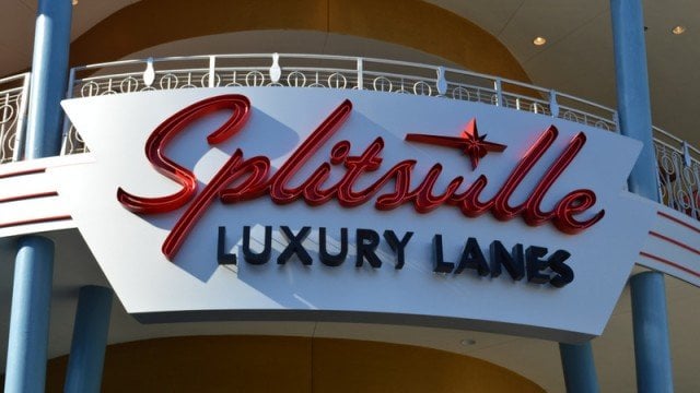 A sign with red and black text reads "Splitsville Luxury Lanes" on the exterior of a building, with blue columns and a curved white balcony above.