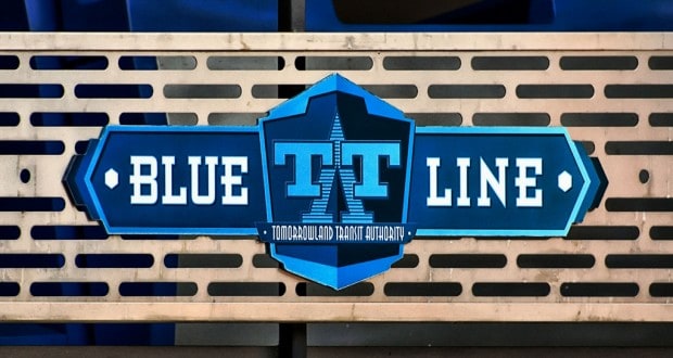BLUE LINE" sign with Tarrant Transit Authority logo on a metal fence, blue seats behind—like Disney signs guiding park guests.