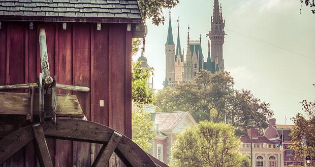 A charming watermill by a gleaming pond and distant castle—like a hidden treasure in Magic Kingdom’s storybook scenery.