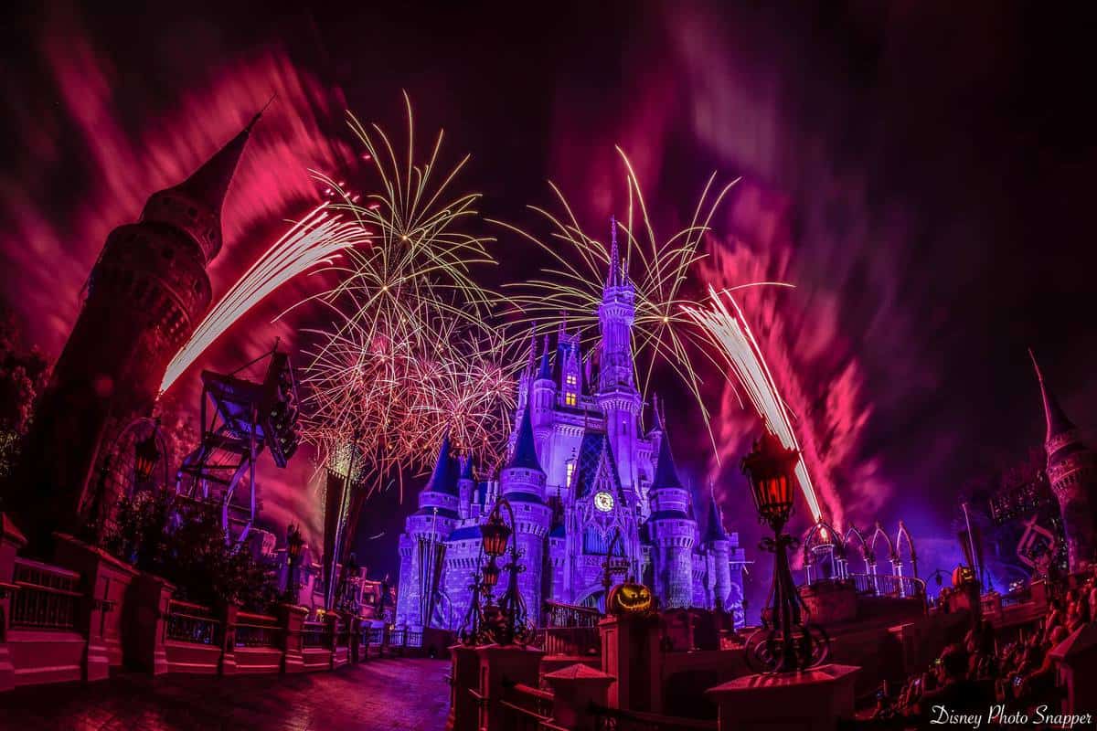 Cinderella Castle shines in pink and purple as fireworks erupt overhead, Halloween decor amplifying the Disney World magic.