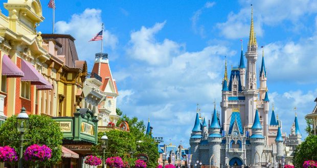 Colorful storefronts line Main Street, leading to Cinderella Castle beneath a bright blue sky at Walt Disney World.
