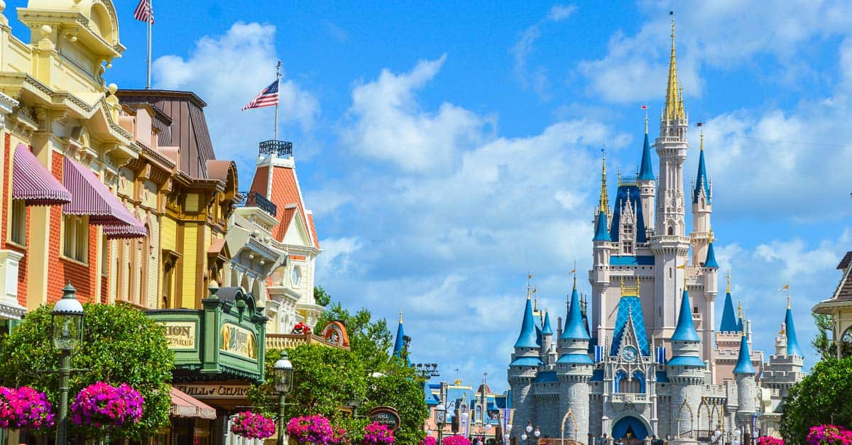 Colorful storefronts line Main Street, leading to Cinderella Castle beneath a bright blue sky at Walt Disney World.