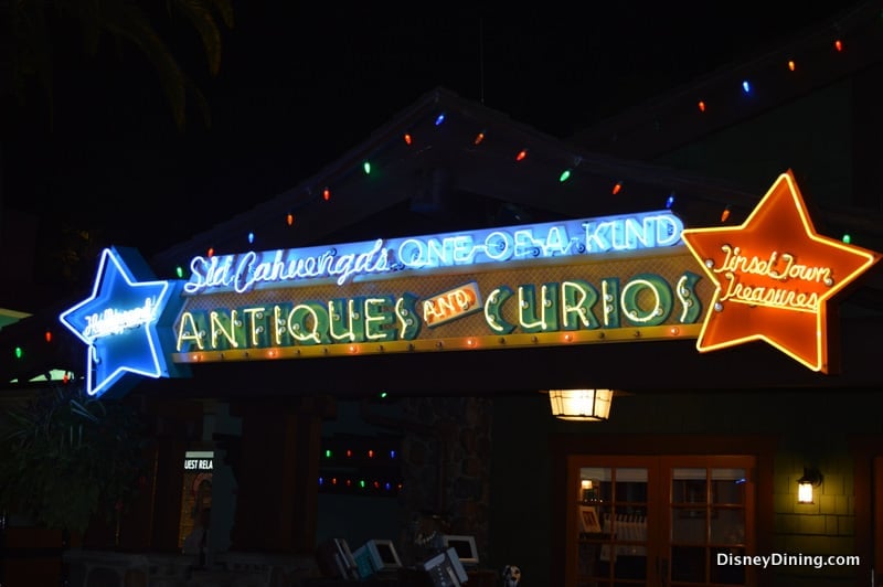 A glowing "Antiques and Curios" neon dazzles Hollywood Boulevard, channeling classic theme park magic and hidden adventures.