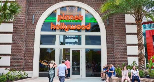 Guests stroll by Planet Hollywood’s neon-lit entrance, a Disney Springs hotspot for dining and vibrant entertainment.
