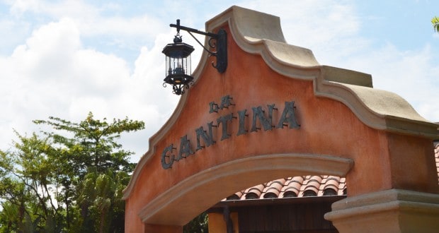 La Cantina de San Angel’s stucco archway and lantern beckon EPCOT guests, framed by a partly cloudy Florida sky.