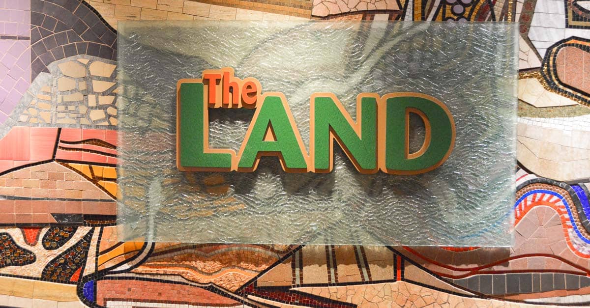 The LAND" sign on a sleek glass panel pops against a vibrant mosaic wall inside Epcot's iconic Land Pavilion at Disney World.