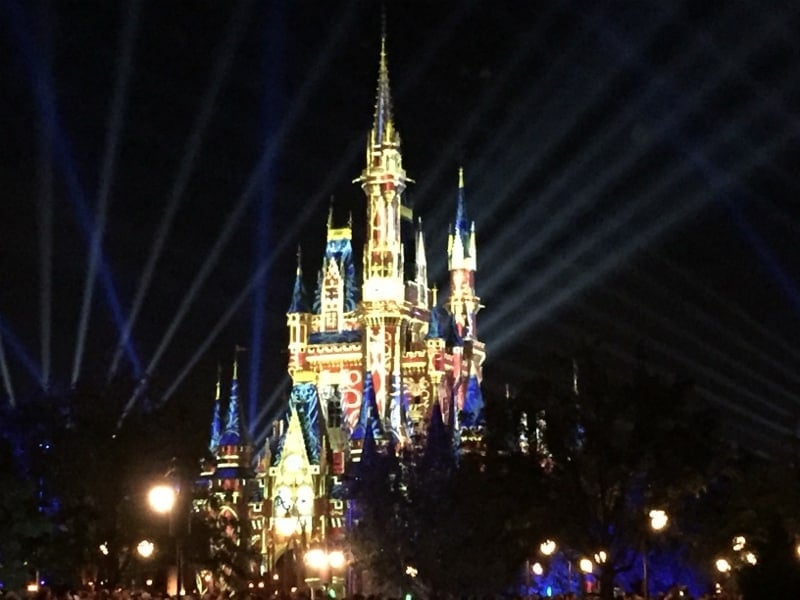 Cinderella Castle aglow in vibrant lights and dazzling beams, enchanting guests during Disney World’s iconic nighttime spectaculars.