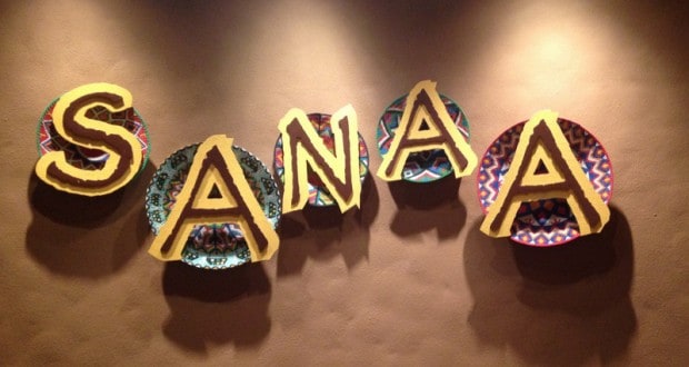 Vibrant SANAA letters on patterned plates pop against a tan wall, embodying Disney dining magic at Walt Disney World.