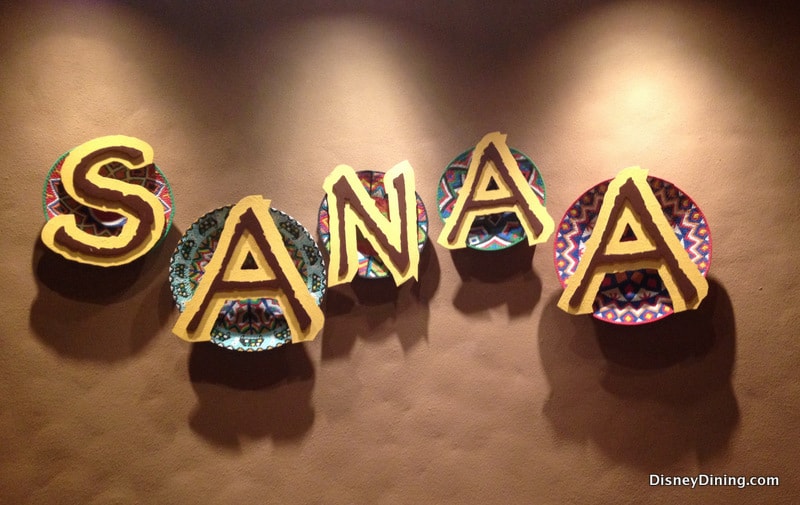 Vibrant SANAA letters on patterned plates pop against a tan wall, embodying Disney dining magic at Walt Disney World.