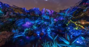 Pandora’s glowing alien landscape dazzles with vivid lights, rocky paths, and otherworldly plants beneath Disney’s magical night sky.