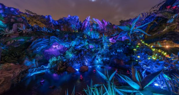 Pandora’s glowing alien landscape dazzles with vivid lights, rocky paths, and otherworldly plants beneath Disney’s magical night sky.