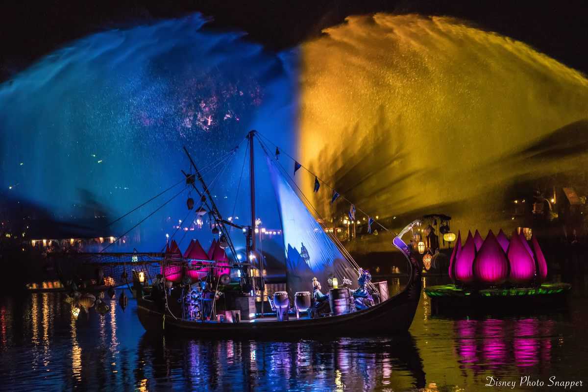 A live show boat glides past vibrant fountains and glowing lotus floats, lighting up the night at Disney’s Animal Kingdom.