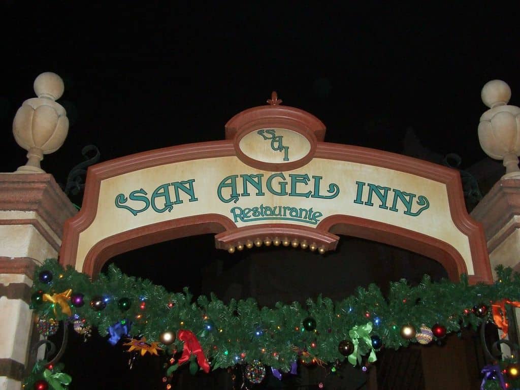 San Angel Inn Restaurante sign at Walt Disney World glowing amid festive garland and ornaments, capturing park holiday magic.
