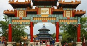 Vibrant Chinese archway at Epcot China Pavilion, framing a pagoda in lush gardens—Disney World magic at its finest.