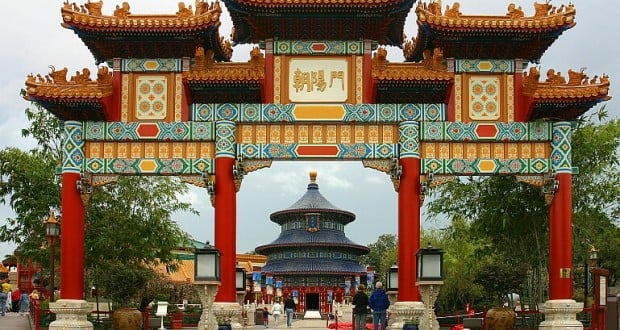 Vibrant Chinese archway at Epcot China Pavilion, framing a pagoda in lush gardens—Disney World magic at its finest.