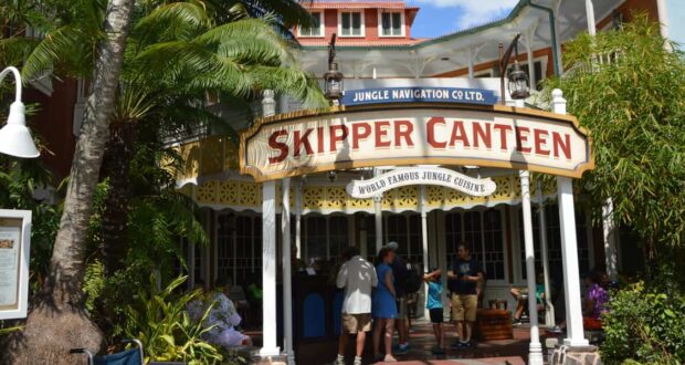 Guests gather outside the Skipper Canteen at Magic Kingdom, immersed in exotic jungle theming and vibrant greenery.