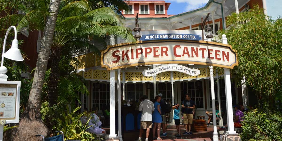 Guests gather outside the Skipper Canteen at Magic Kingdom, immersed in exotic jungle theming and vibrant greenery.