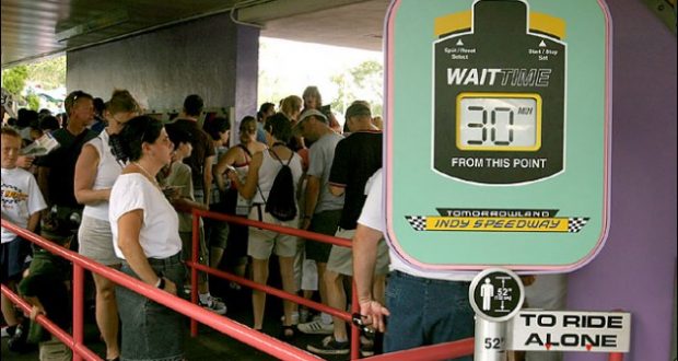 Visitors queue in Tomorrowland as the Indy Speedway sign posts a 30-minute wait time at Disney World.