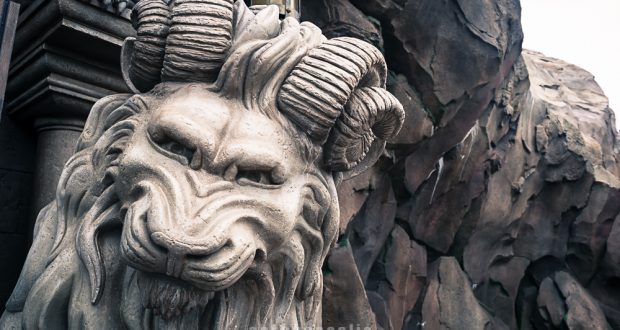 Majestic lion statue with ram horns, like the mythical decor at Disney World’s immersive themed restaurants, rocky and dramatic backdrop.
