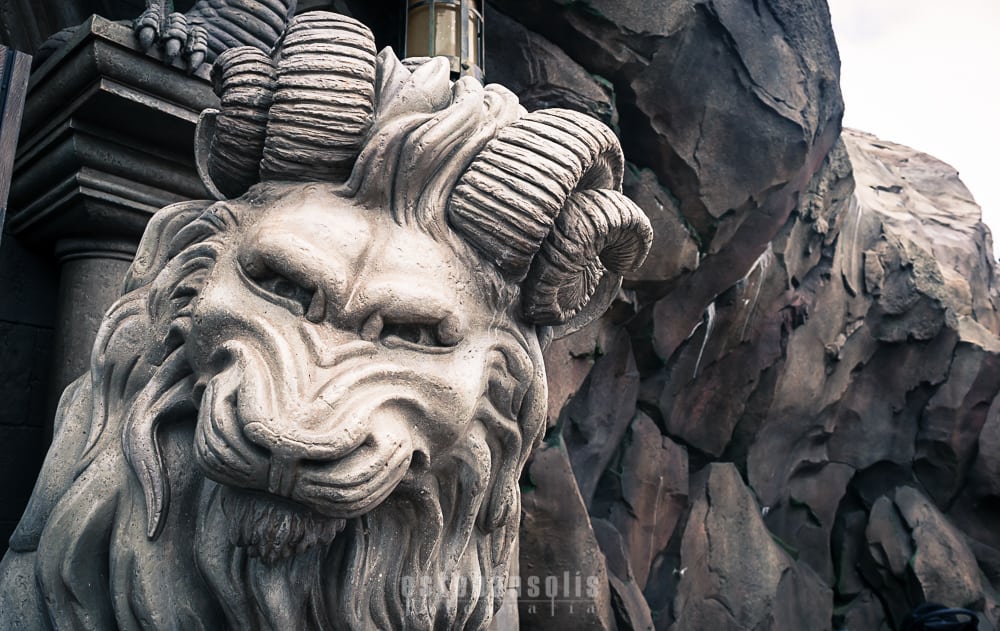 Majestic lion statue with ram horns, like the mythical decor at Disney World’s immersive themed restaurants, rocky and dramatic backdrop.
