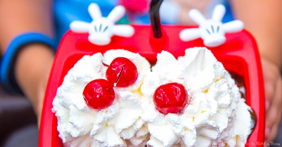 Indulge in this Disney World treat—whipped cream and cherries on top, served in a red Mickey Mouse bowl for magical ice cream fun!.