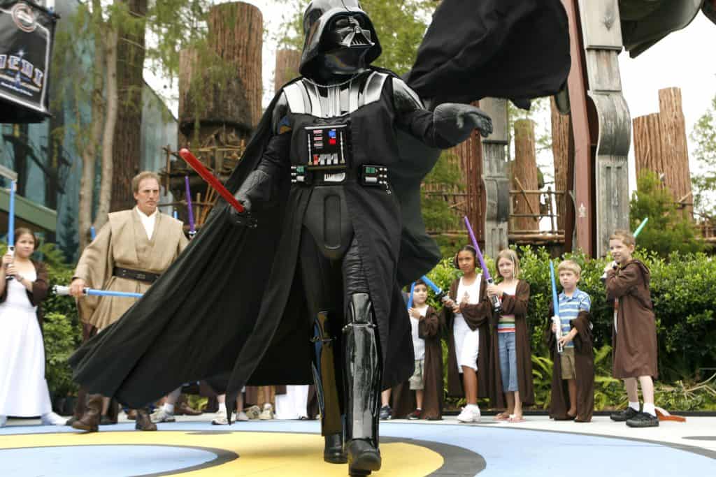 Darth Vader leads young Jedi with toy lightsabers at Walt Disney World, bringing Star Wars adventures to life for guests.