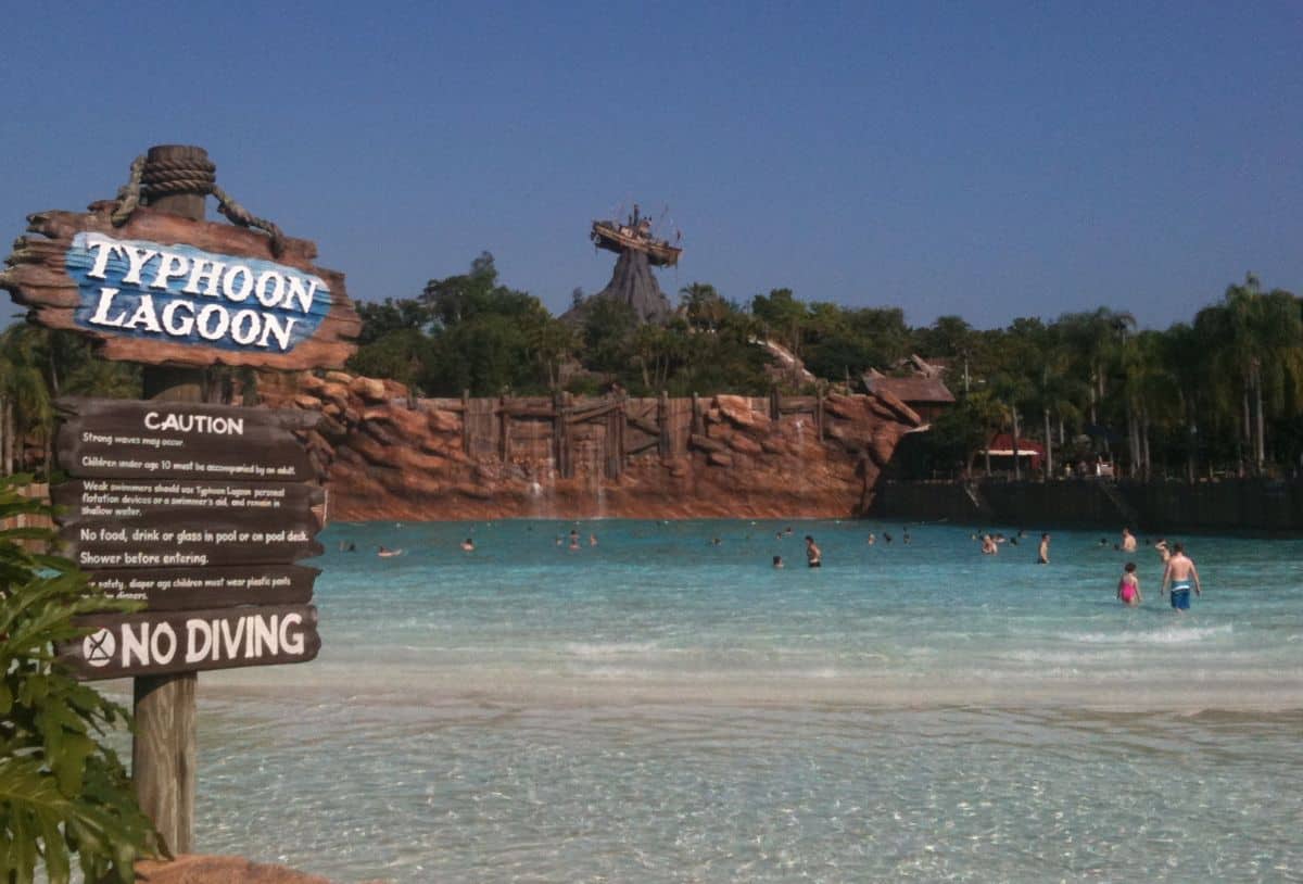 Typhoon Lagoon’s iconic wave pool with guests enjoying the surf, set against the backdrop of Miss Tilly shipwreck on Mt. Mayday.