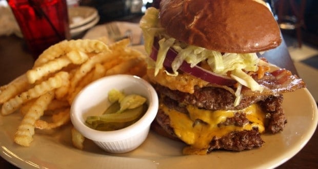 Double cheeseburger with lettuce, bacon, and onion, plus crinkle fries and pickles, served at Walt Disney World for park guests.