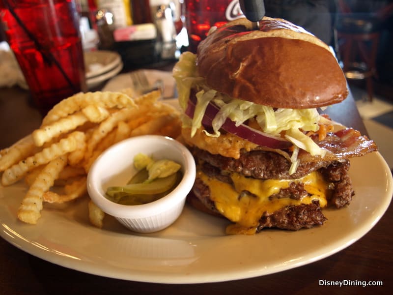 Double cheeseburger with lettuce, bacon, and onion, plus crinkle fries and pickles, served at Walt Disney World for park guests.