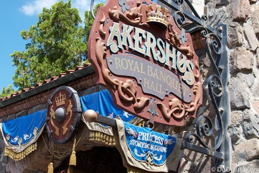 Akershus Royal Banquet Hall with blue banners invites guests to dine with Disney Princesses in a storybook castle setting.
