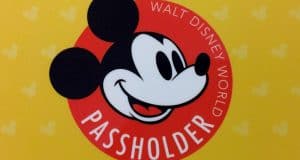 Bright yellow Disney World Passholder card featuring Mickey Mouse's face in a red circle, unlocking annual member perks.
