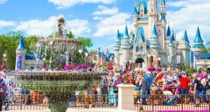 Guests gather by Cinderella Castle with its iconic blue spires and sparkling fountain on a sunny day at Disney World.