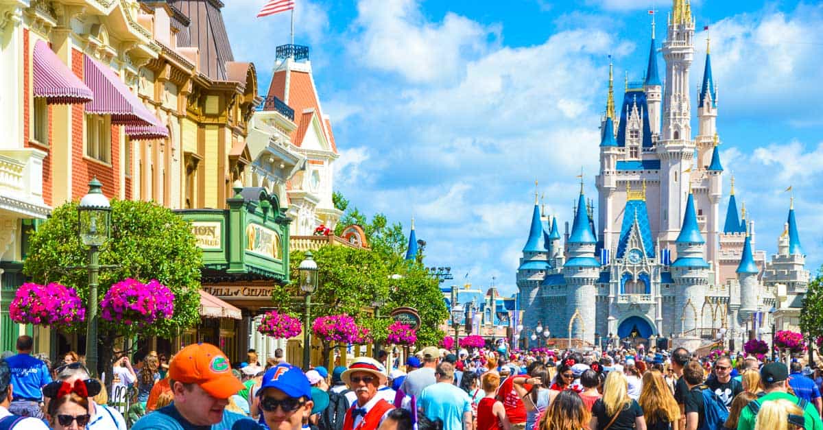 Guests stroll along Main Street, U.S.A. at Disney World, with Cinderella Castle and vibrant storefronts framing the magical scene.