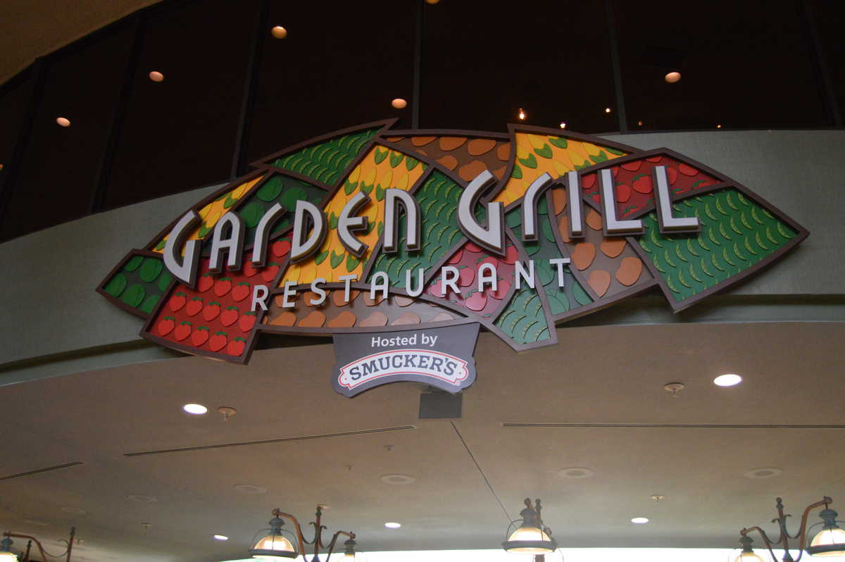 Stained glass "Garden Grill Restaurant" sign with "Hosted by Smuckers"—a hotspot for Hidden Mickey hunters at EPCOT.