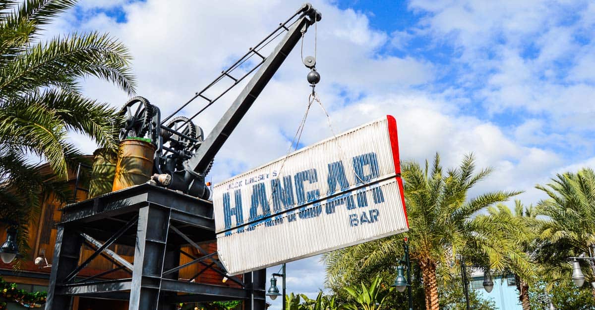 A crane installs the iconic Hangar Bar sign among palm trees at Disney Springs, signaling a new hotspot for Disney fans.