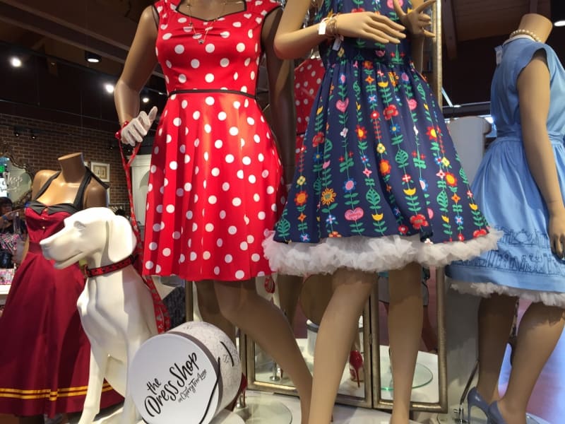 Three mannequins in playful, retro Disney-inspired dresses and a white dog mannequin liven up a shop perfect for park fans.