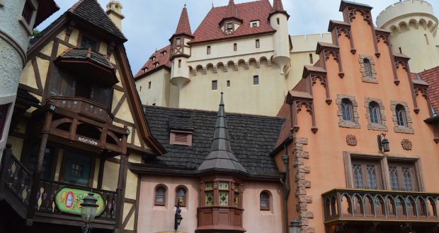 Vibrant Bavarian village architecture and a storybook castle at EPCOT’s Germany Pavilion, set beneath dramatic clouds.