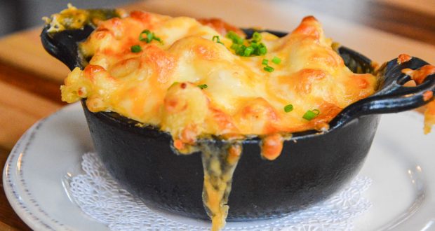 Cheesy baked macaroni and cheese in a black dish with chives, served on a white plate—iconic Disney World comfort food.
