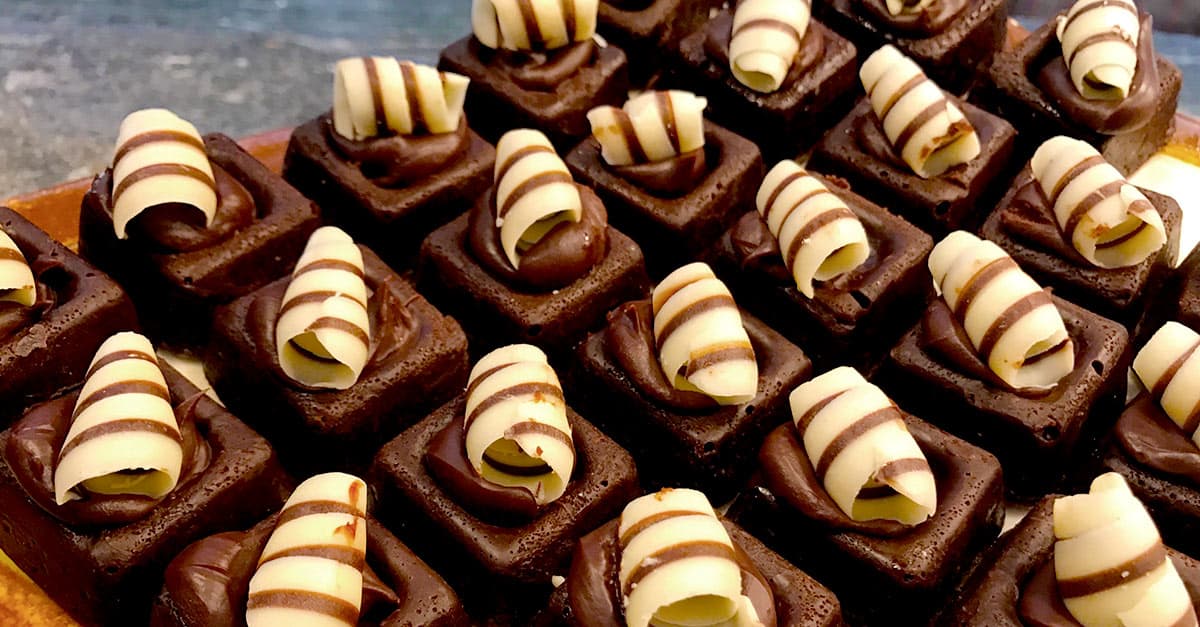 Disney World-inspired brownies lined up with dark chocolate swirls and white chocolate curls, just like park dessert treats.