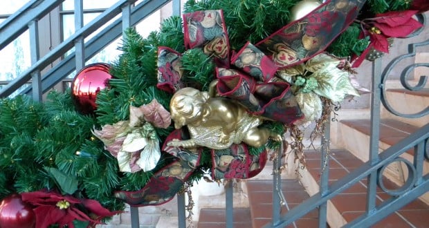 Christmas garland with red ornaments, a gold angel, and bows trims the staircase, echoing Epcot Italy Pavilion holiday décor.