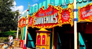 Big Top Souvenirs at Magic Kingdom, vibrant circus décor and lively signage, with a guest pushing a stroller outside the shop.