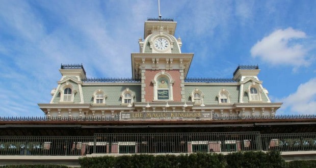 Magic Kingdom’s classic train station and clock tower, framed by lush bushes and bright skies, is an iconic Disney World photo spot.
