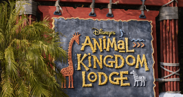 Disney’s Animal Kingdom Lodge sign with giraffe and zebra art, surrounded by tropical greenery near bustling Kidani Village.