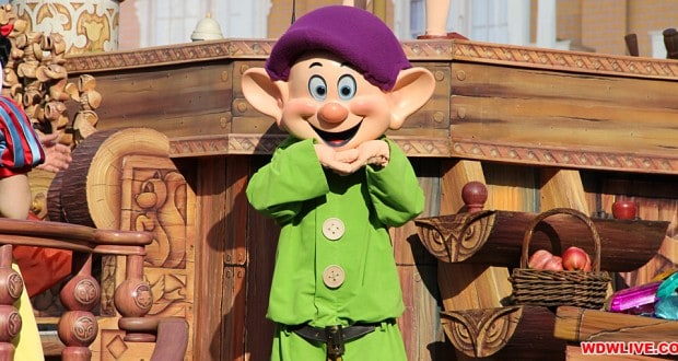 Dopey beams in front of a wooden parade float at Walt Disney World, showcasing the excitement of solo park adventures.