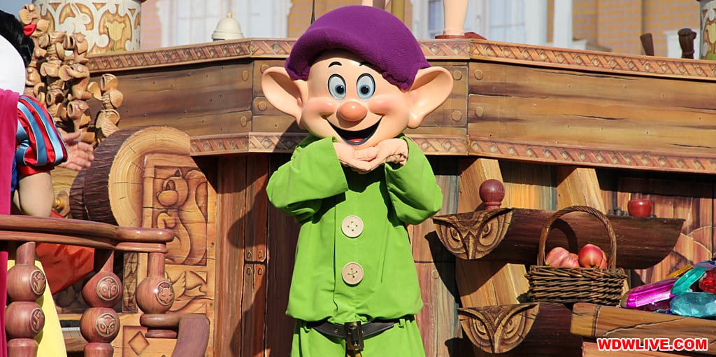 Dopey beams in front of a wooden parade float at Walt Disney World, showcasing the excitement of solo park adventures.