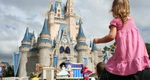 A young guest rides on shoulders, enjoying a dazzling castle show amid the lively crowds at Walt Disney World.