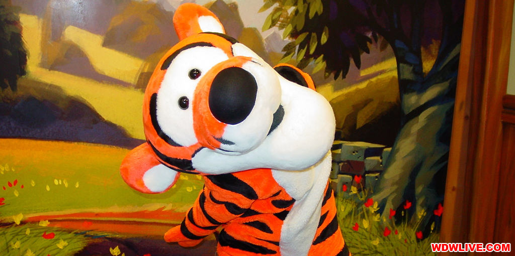 Tigger beams and strikes a playful pose in front of a themed backdrop, ready for magical meet and greets at Walt Disney World.