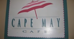 Cape May Cafe sign at Disney World with a red and white beach umbrella—capture the resort’s coastal vibes before you dine.
