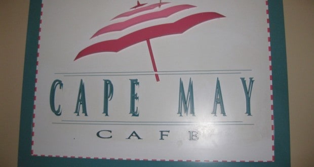 Cape May Cafe sign at Disney World with a red and white beach umbrella—capture the resort’s coastal vibes before you dine.
