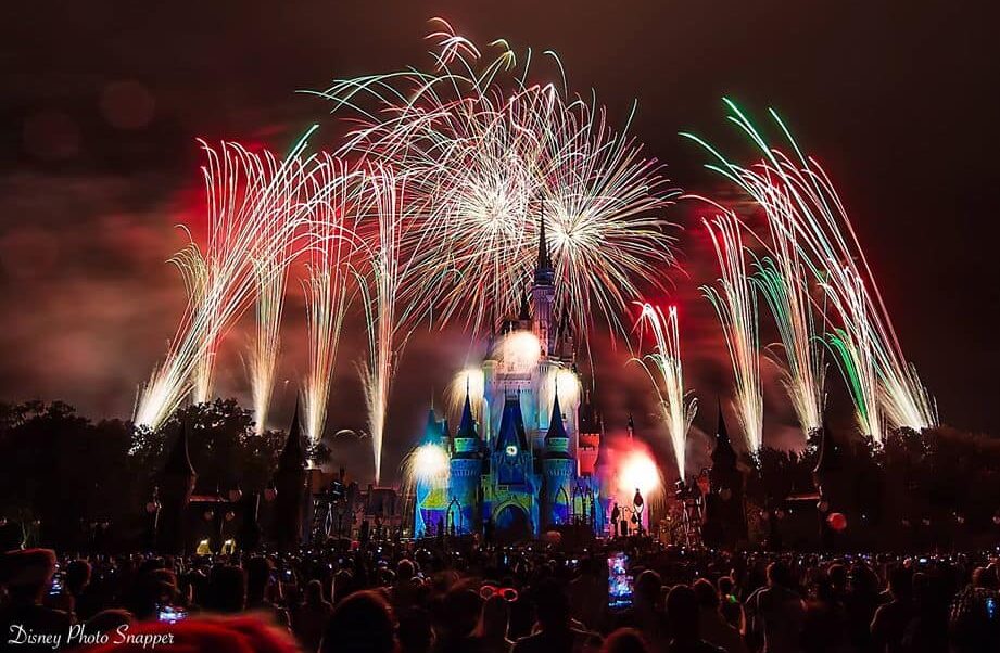 Dazzling fireworks illuminate Cinderella Castle at night as Disney World guests capture the magical show on their phones.
